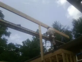 Carpenter setting a ridge beam over a new addition frame — Ice Dam Removal by Roofing Brothers in Magazine