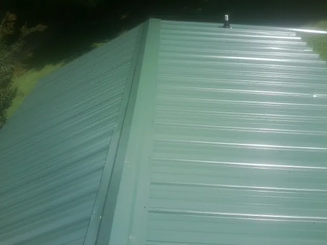 New green metal panels meeting at the ridge of a roof — Flat Roof Repair work by our crew in Magazine