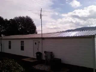 New metal roof on a single wide mobile home with a TV antenna in Magazine