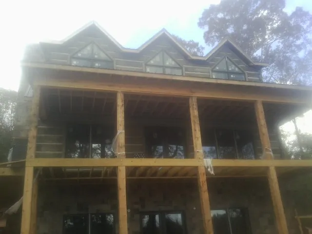 Dormers and porch framing on a large log home under construction — Roof Coating work by our crew in Magazine