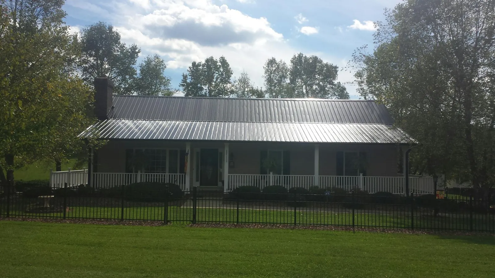 Gray metal roof on a brick ranch with a full width front porch — Gutter Guard Installation work by our crew in Magazine