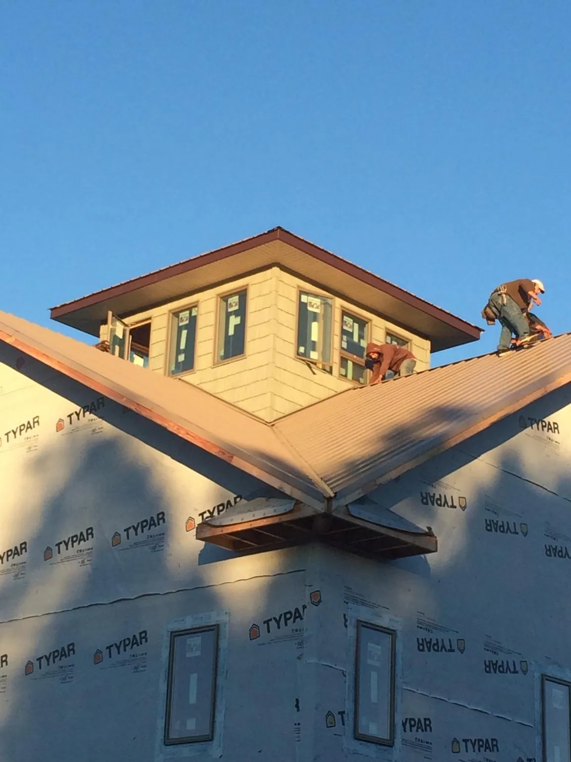 Roofers working around a rooftop cupola on a new metal roof at sunset — Roof Waterproofing in Magazine by Roofing Brothers